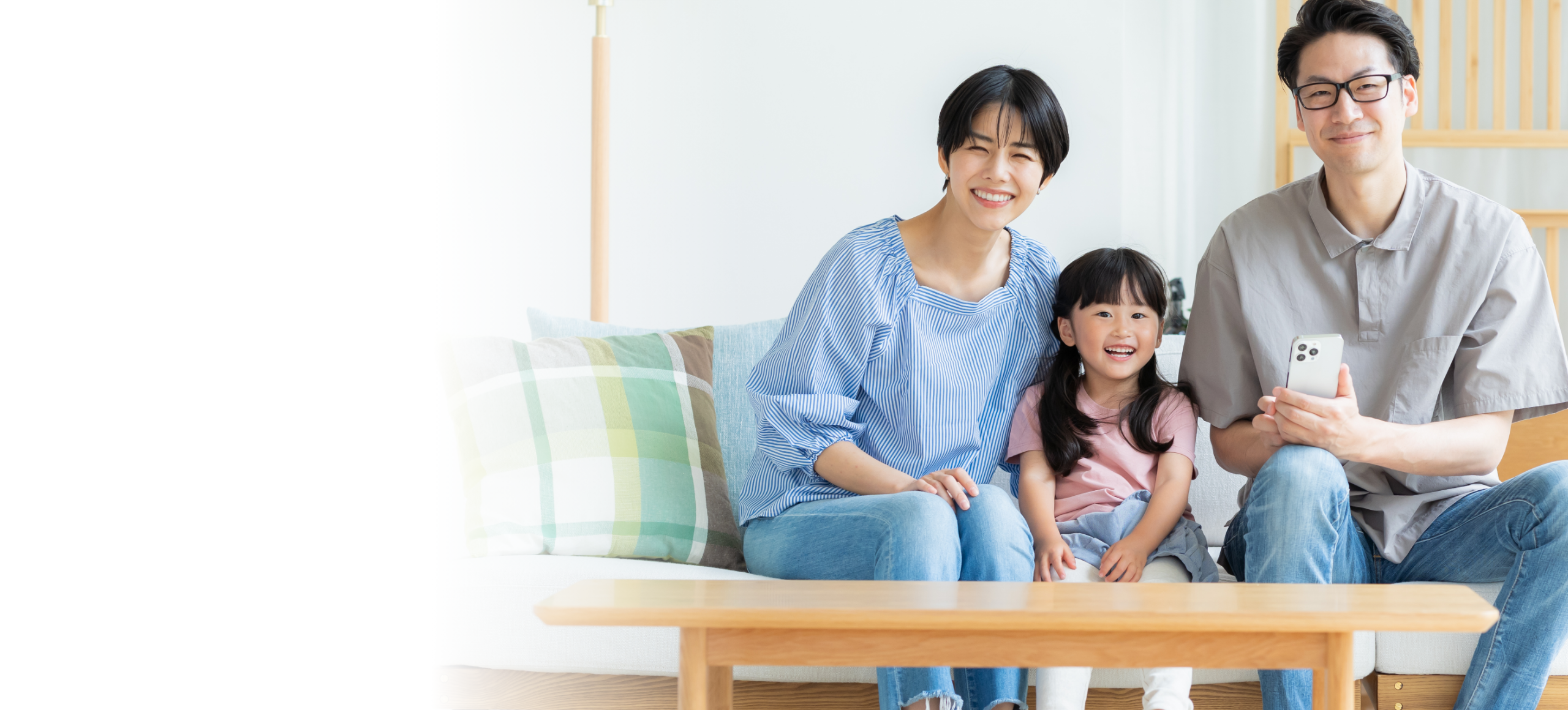 スマートフォンを持つ家族がリビングでくつろいでいる様子